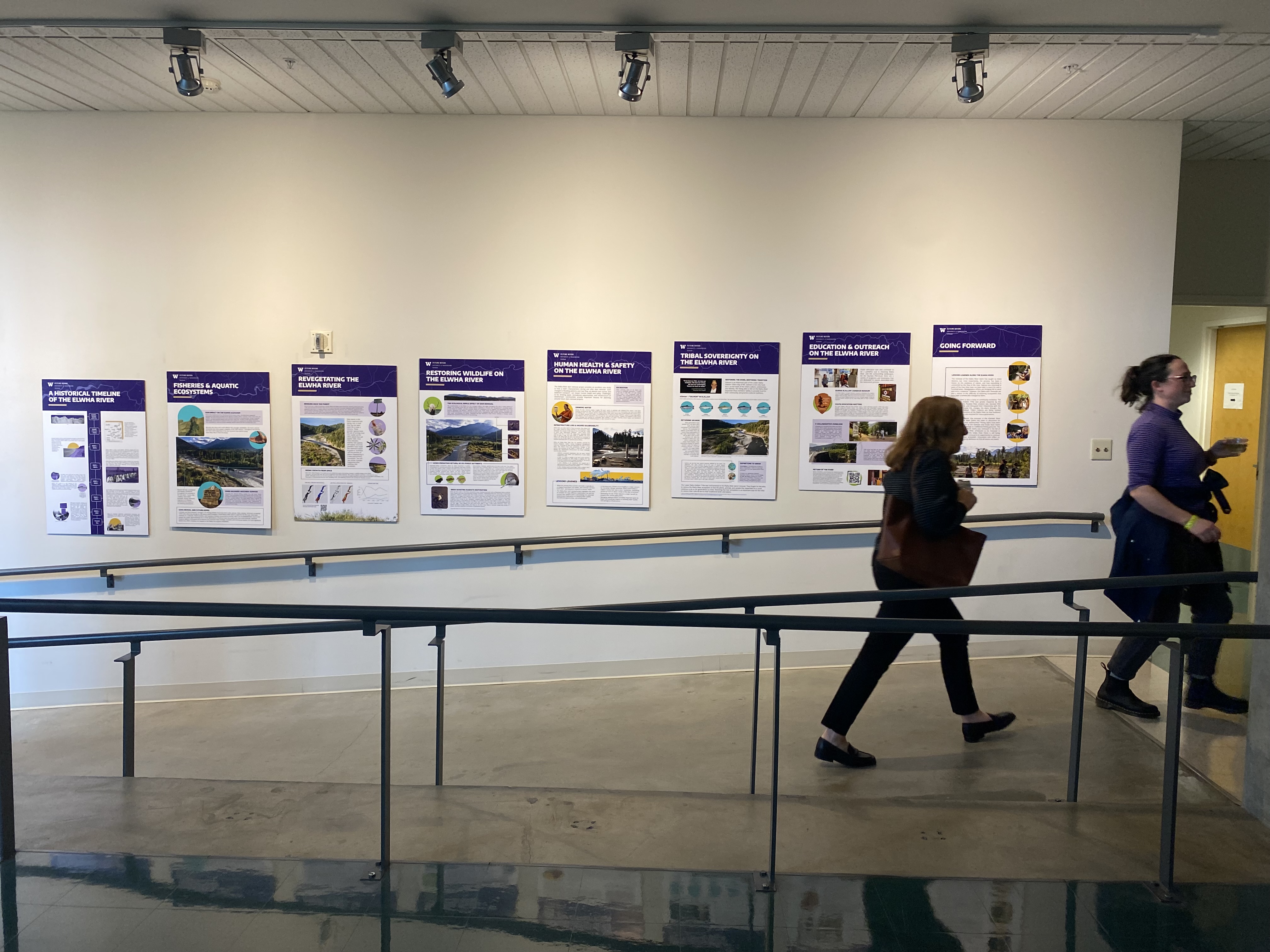 Attendees walking past the Future Rivers poster installation at UW